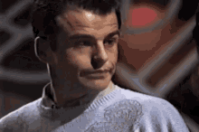 a close up of a man wearing a sweater and looking at the camera .