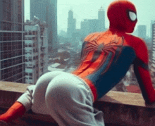 a man in a spiderman costume is sitting on a ledge overlooking a city