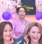 three women are posing for a picture in front of balloons and a sign that says " coa "