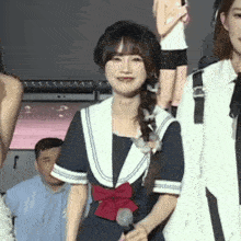 a girl in a sailor outfit is holding a microphone in her hand .