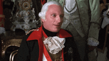 a man in a red jacket and white wig has a medal on his chest