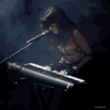 a woman singing into a microphone while playing a keyboard with gifcamilas written on the bottom