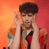 a young man in a colorful shirt is making a funny face