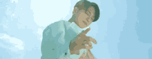 a man in a white jacket is making a heart shape with his hands against a blue sky .