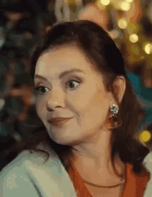 a woman wearing earrings and a necklace is smiling .