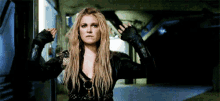 a woman is standing in a dark room with her arms outstretched and a gun in her hand .
