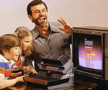 a man and two children are playing a video game on an atari system