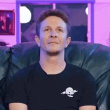 a man is sitting in a chair wearing a black shirt with a skull and crossbones on it .