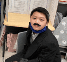 a boy wearing a fake mustache and a blue scarf around his neck