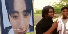 a group of young men are standing next to each other in front of a picture of a man 's face .