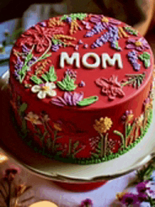 a red mother 's day cake with flowers and the word mom on it