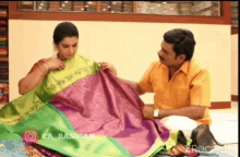 a man is helping a woman choose a saree