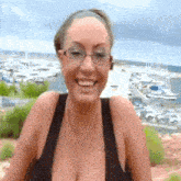 a woman with glasses is smiling in front of a marina