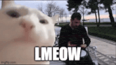 a man is sitting on a bench with a cat looking at him and the cat is saying lmeow .
