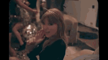 a woman is sitting on a couch with a disco ball in the background and smiling .