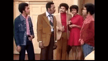 a group of black men and women are standing next to each other in a living room .