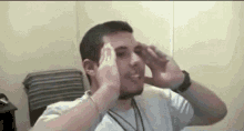 a man in a white shirt is holding his head in pain .
