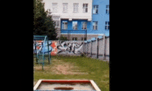 a sandbox in front of a building with graffiti on the wall