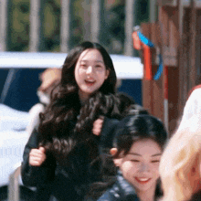 a woman with long hair is smiling while walking with another woman .