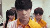 a man in a yellow shirt stands in a line with other people