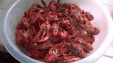 a white bowl filled with red crayfish on a white surface