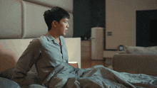 a man in a grey shirt is laying in bed with his arms outstretched