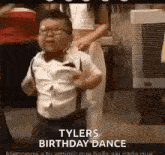 a little boy is dancing at a birthday party with a woman standing behind him .