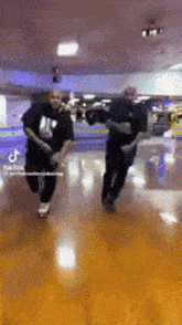 a couple of men are dancing on a bowling alley .