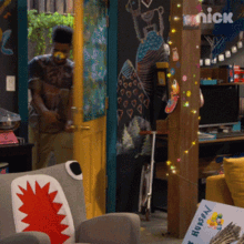 a man is standing in a room with a nick sign on the wall