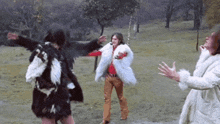 three people in fur coats are dancing in a park .