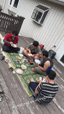 a group of men are sitting on a deck eating food
