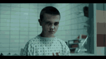 a young boy in a hospital gown with blood on his face .
