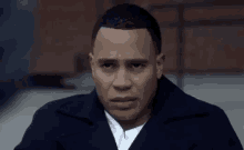 a man in a black coat and white shirt is looking at the camera with a sad look on his face .