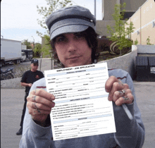 a man in a hat is holding up an employment job application form
