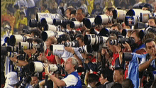 a crowd of people are using canon cameras to take pictures