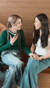 two women sitting next to each other with one wearing a green sweater