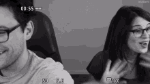 a black and white photo of a man and a woman with the time of 00:55 on the bottom