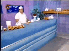 a man is standing behind a counter in front of a chalkboard that says 1:15