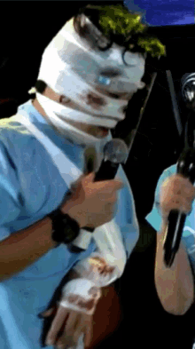 a man with a bandage on his face holds a microphone