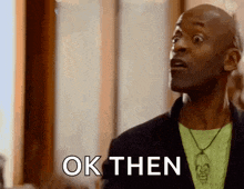 a man in a green shirt is making a funny face and saying `` ok then '' .