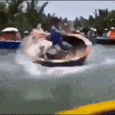 a man in a blue shirt is riding a boat in the water