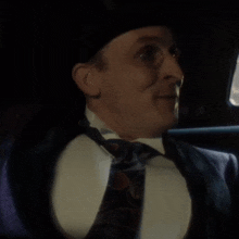 a man in a suit and tie is sitting in a car and smiling .
