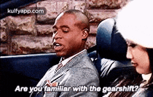 a man and a woman are sitting in a car and the man is asking the woman if she is familiar with the gearshift .