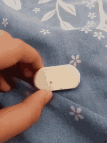 a person is holding a white eraser on a bed