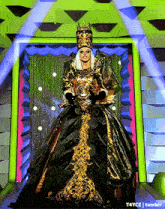a drag queen in a green and gold dress and crown