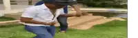 a man in a hat is dancing in the grass in front of a pool .