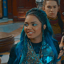 a woman with blue hair and braids is standing next to a man