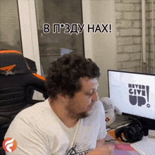 a man sitting in front of a computer with the words never give up on it