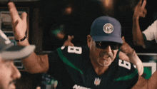 a man wearing a hat and sunglasses with the number 8 on his jersey