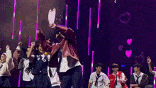a group of young people are dancing on a stage in front of a purple background .